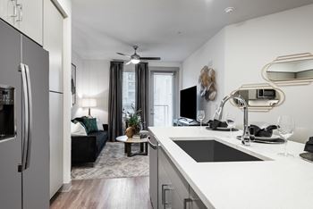 a kitchen with a sink and a tv in a room with a couch and a coffee table